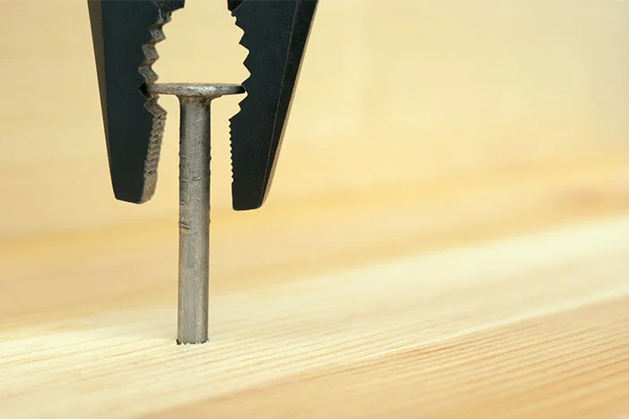 Zange zieht Nagel aus Holz